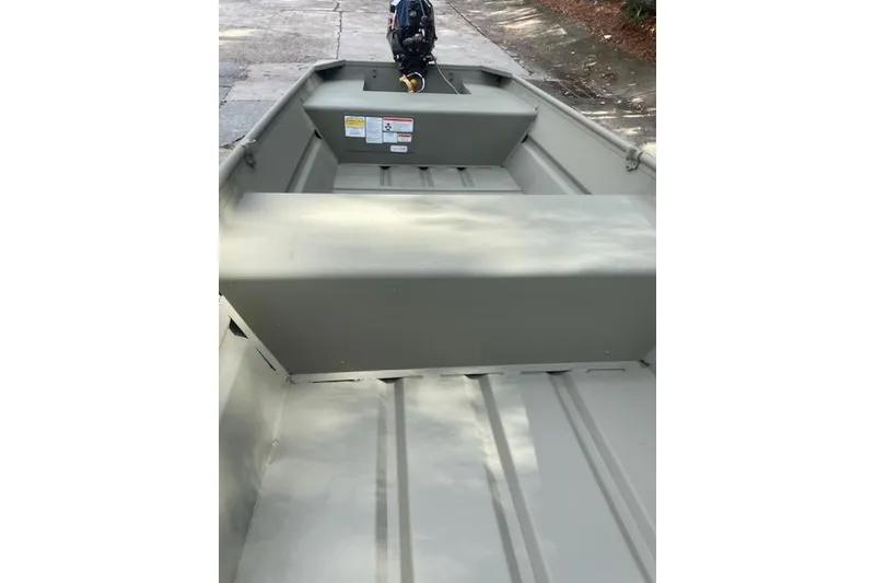 Slide: The Image of 2025 Tracker Grizzly 14 Jon boat interior with motor, parked on concrete. - 60