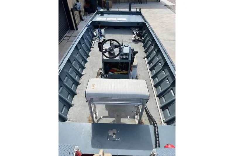 Slide: The Image of 1999 Aluminum Boat interior with steering console and seating, docked in a garage area. - 10