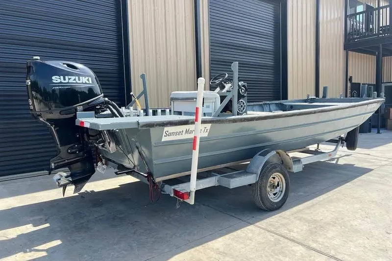 Slide: The Image of 1999 Aluminum Boat with Suzuki outboard motor on trailer, parked outside a building. - 2
