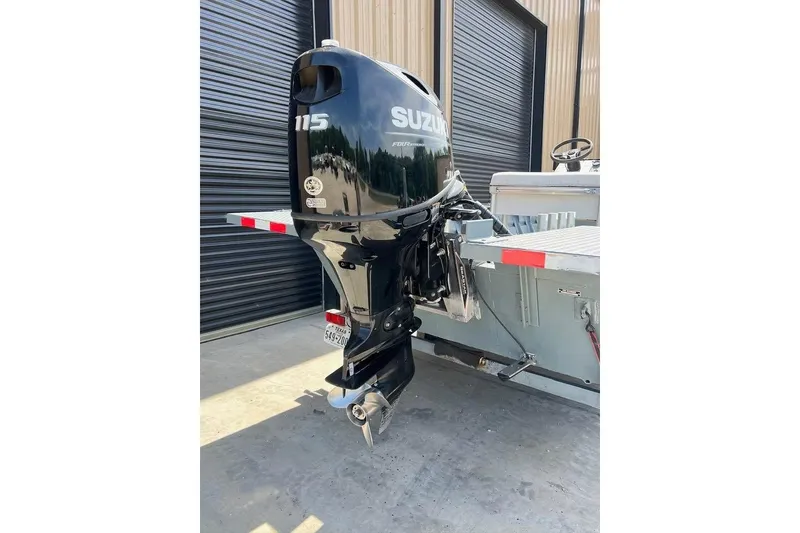 Slide: The Image of 1999 Aluminum Boat with Suzuki 115 outboard motor, parked near industrial building. - 7