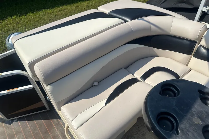 Slide: The Image of 2013 Sweetwater 2086 RE boat interior with beige and black seating, cup holders, and outdoor setting. - 14