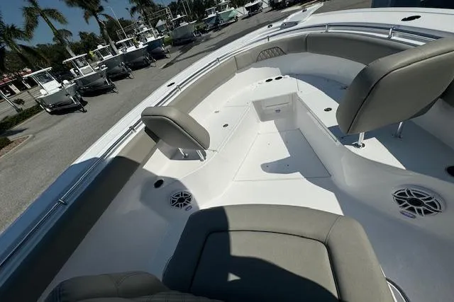 Slide: The Image of 2025 Sportsman Open 282 Center Console boat interior with seating and speakers, docked under palm trees. - 15