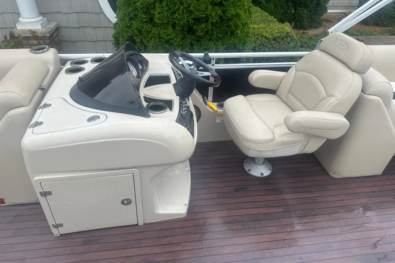 Slide: The Image of 2013 Harris Solstice 220 boat helm with beige captain's chair and wooden deck. - 6