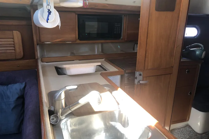 Slide: The Image of 2001 Catalina 34 Mk II yacht interior with kitchen sink, microwave, and wooden cabinetry. - 15