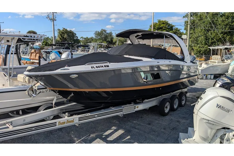 Slide: The Image of 2019 Four Winns H290 OB boat on trailer, parked in marina with other boats. - 24
