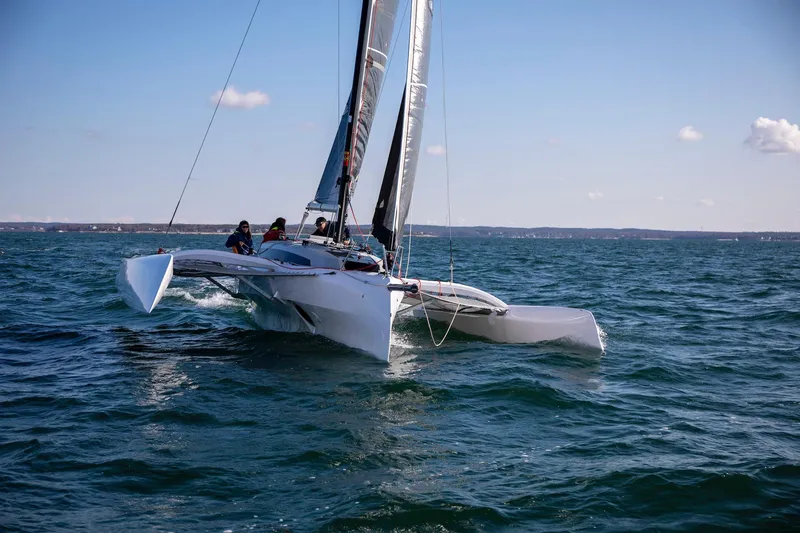 Slide: The Image of 2022 Corsair 880 Sport trimaran sailing on open water under clear skies. - 2