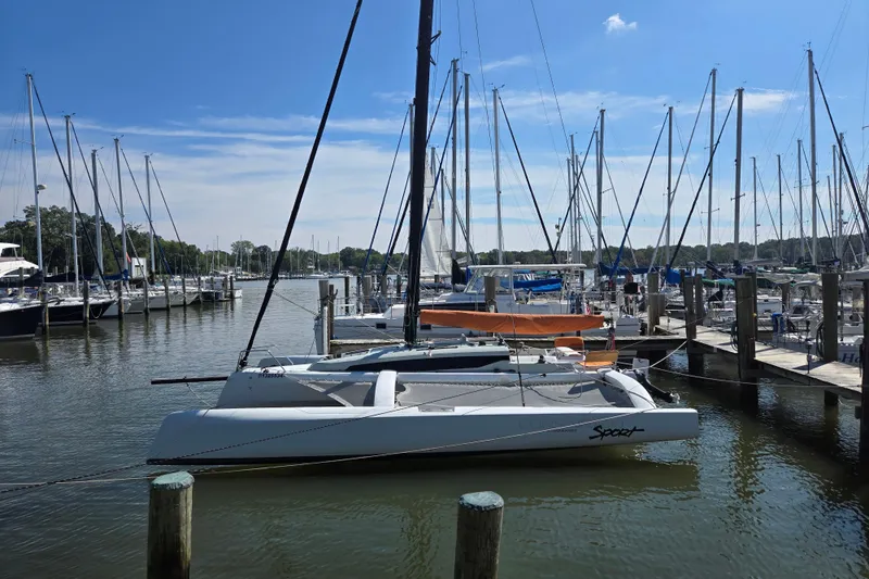 Slide: The Image of Sailboats docked at a marina, featuring a 2022 Corsair 880 Sport trimaran. - 5