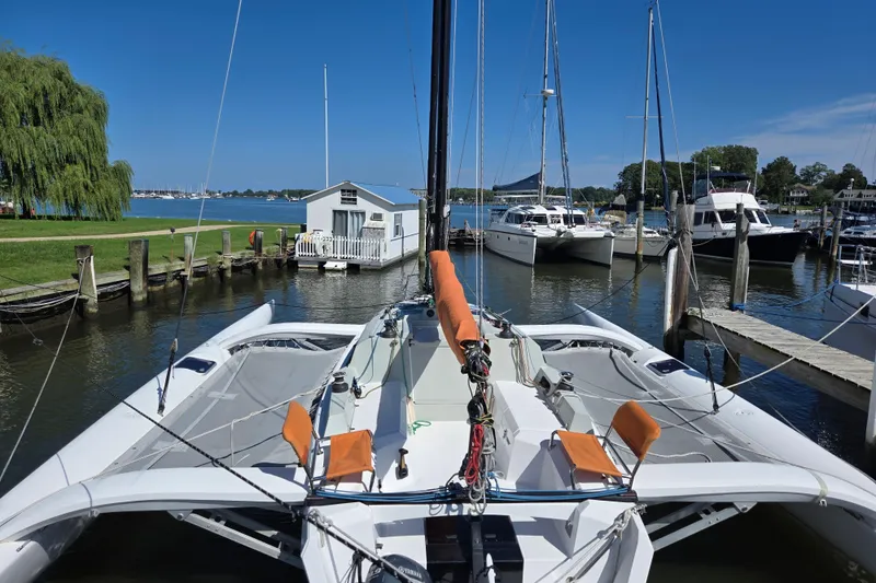 Slide: The Image of 2022 Corsair 880 Sport trimaran docked at a marina with clear blue skies. - 6