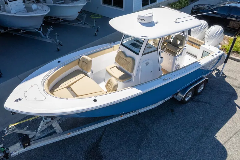 Slide: The Image of 2026 Sportsman Open 282 Center Console boat on trailer, blue hull, parked outside a building. - 2