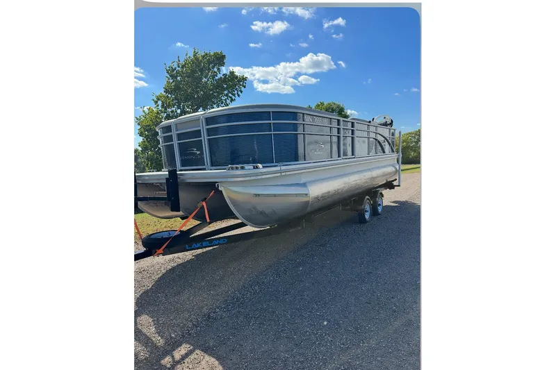 Slide: The Image of 2019 Bennington SX 22 Fishing pontoon boat on trailer under blue sky. - 11