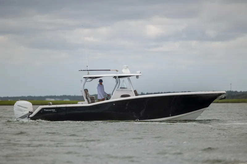 Slide: The Image of 2020 Tidewater 320 CC Adventure boat cruising on a calm waterway under cloudy skies. - 1