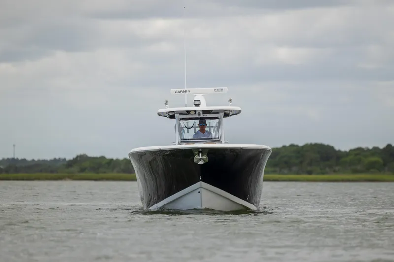Slide: The Image of 2020 Tidewater 320 CC Adventure boat on water, front view, overcast sky. - 10