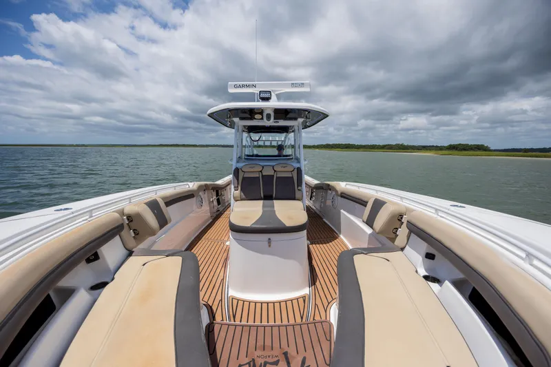 Slide: The Image of 2020 Tidewater 320 CC Adventure boat interior with seating, on a calm lake under cloudy skies. - 24