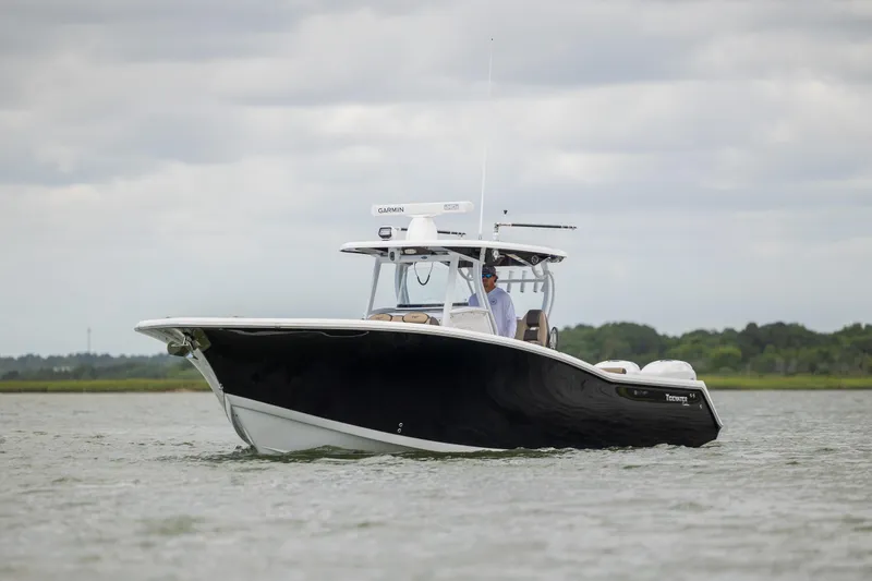 Slide: The Image of 2020 Tidewater 320 CC Adventure boat cruising on calm waters under cloudy skies. - 5