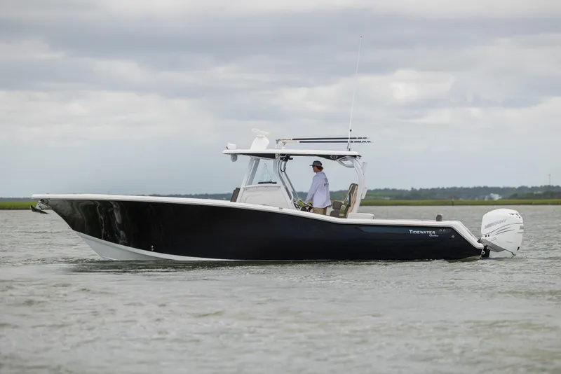 Slide: The Image of 2020 Tidewater 320 CC Adventure boat cruising on calm waters under cloudy skies. - 7