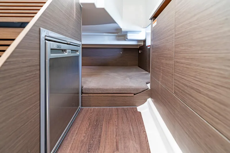 Slide: The Image of 2025 Beneteau Flyer 9 SUNdeck interior cabin with wood finish and compact fridge. - 13