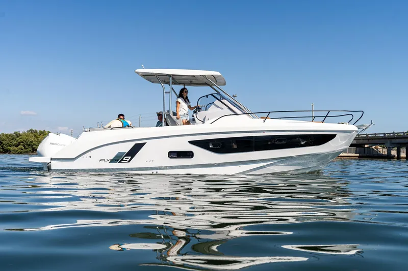 Slide: The Image of 2025 Beneteau Flyer 9 SUNdeck boat cruising on calm water under clear blue sky. - 28