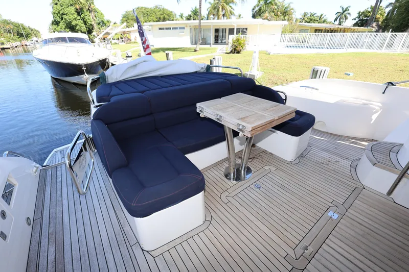Slide: The Image of 2016 Sunseeker Manhattan 55 yacht deck with seating and table, docked by a canal. - 45