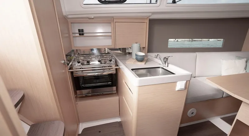 Slide: The Image of Interior of 2025 Beneteau Oceanis 30.1 yacht, featuring a compact kitchen and seating area. - 15