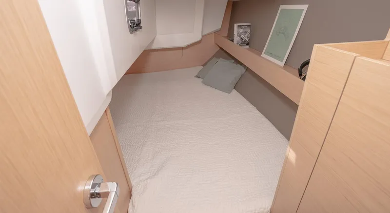 Slide: The Image of 2025 Beneteau Oceanis 30.1 cabin interior with cozy bed and wooden finish. - 17