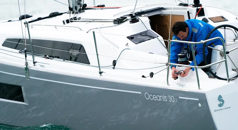 Slide: The Image of 2025 Beneteau Oceanis 30.1 sailboat with person adjusting equipment on deck. - 6