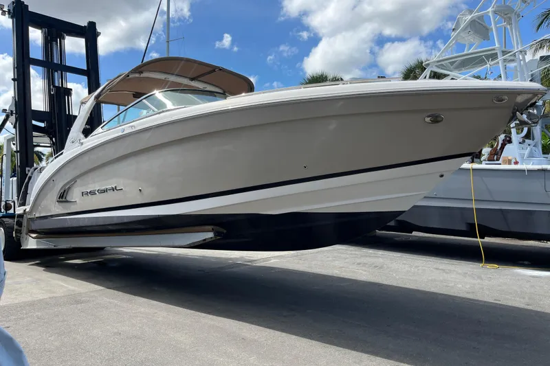 The Image of 2014 Regal 3200 Bowrider boat on a lift under a clear blue sky. - 1