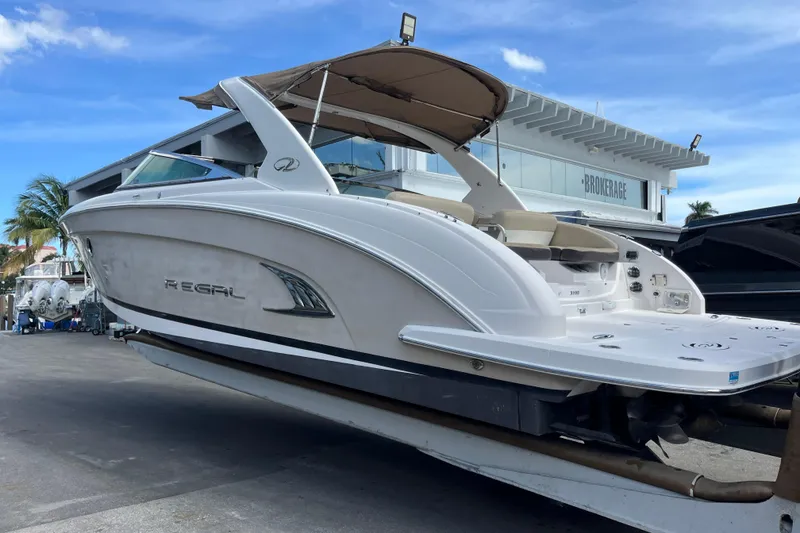 Slide: The Image of 2014 Regal 3200 Bowrider boat on display at a marina with blue sky background. - 3