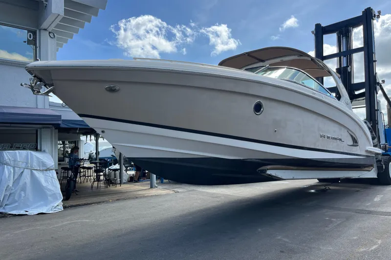 Slide: The Image of 2014 Regal 3200 Bowrider boat lifted at marina, under a blue sky. - 4