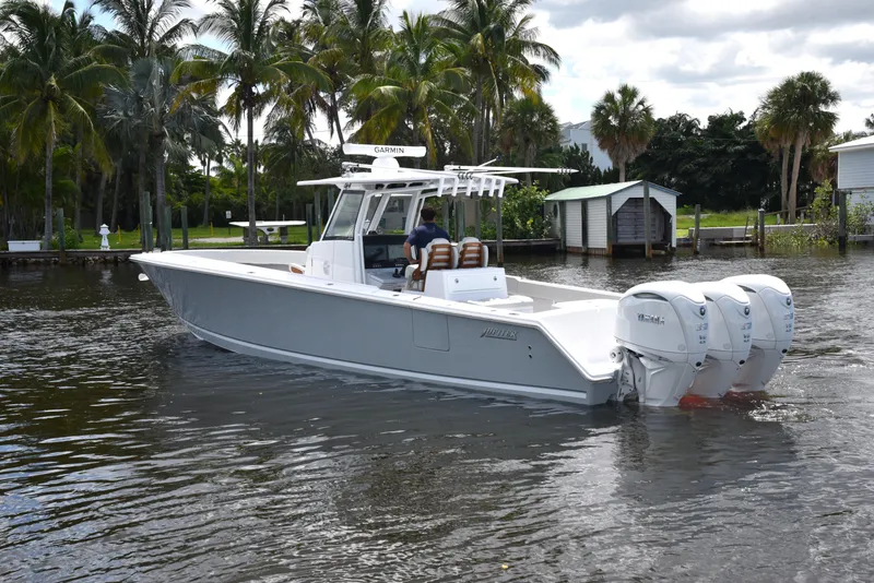 Slide: The Image of 2025 Jupiter 380 LS boat cruising on a calm waterway with palm trees in the background. - 2