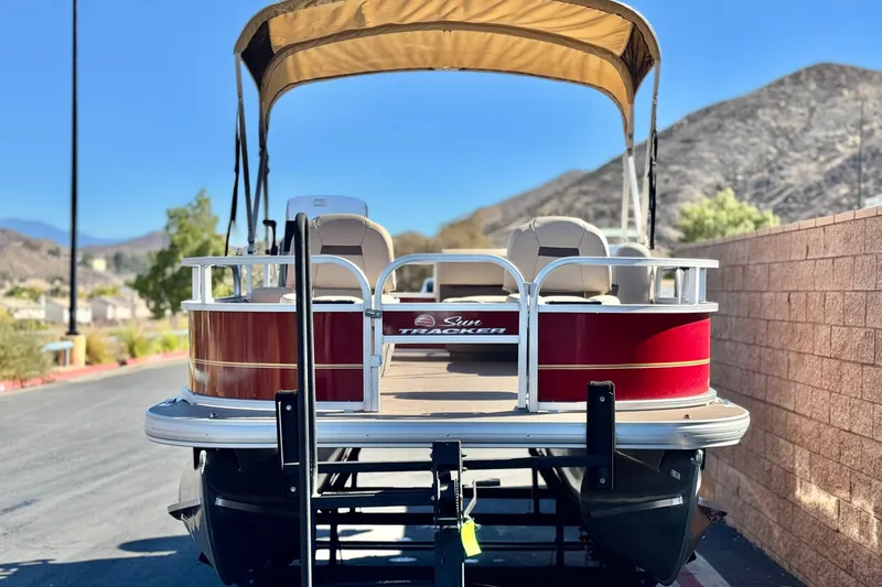 Slide: The Image of 2023 Sun Tracker Bass Buggy 16 XL pontoon boat with canopy, parked near mountains. - 2