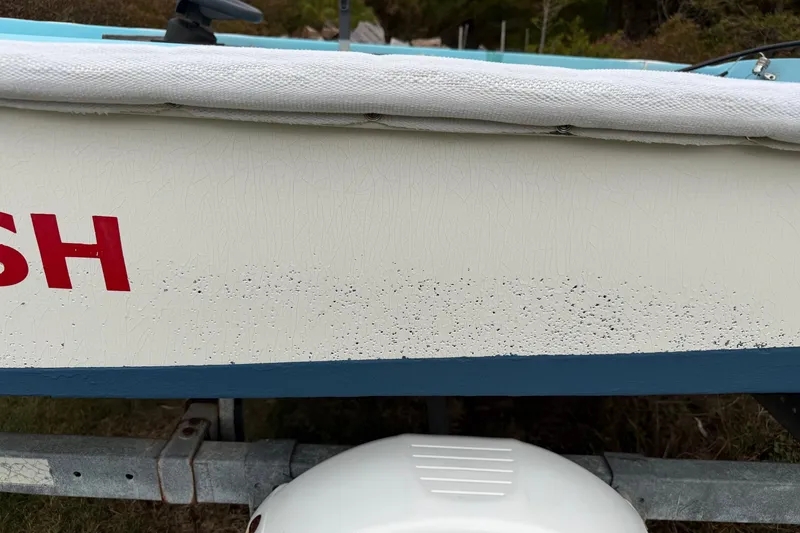 Slide: The Image of Close-up of a 1967 Boston Whaler 13 boat hull with visible wear and red lettering. - 9