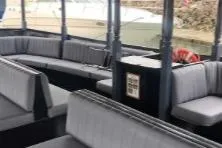 Slide: The Image of Interior of a 1983 Custom Limo Boat with gray seating and open windows. - 10