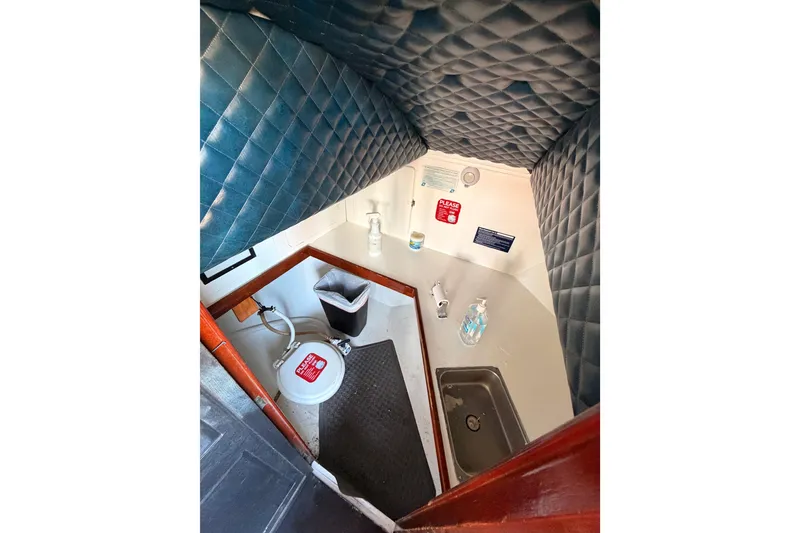 Slide: The Image of Interior of 1983 Custom Limo Boat bathroom with quilted walls and compact amenities. - 16