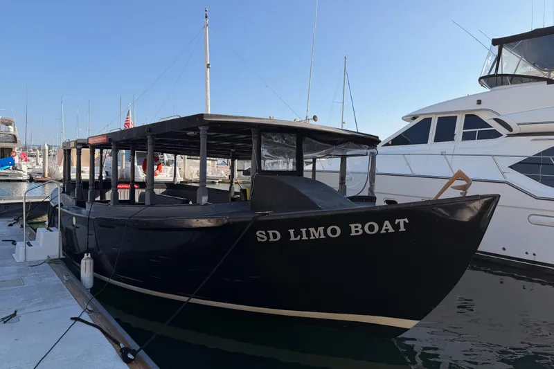 Slide: The Image of Custom 1983 Limo Boat docked at marina, featuring open seating and sleek design. - 2