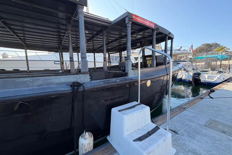 Slide: The Image of Custom 1983 Limo Boat docked, featuring a black exterior and covered seating area. - 6