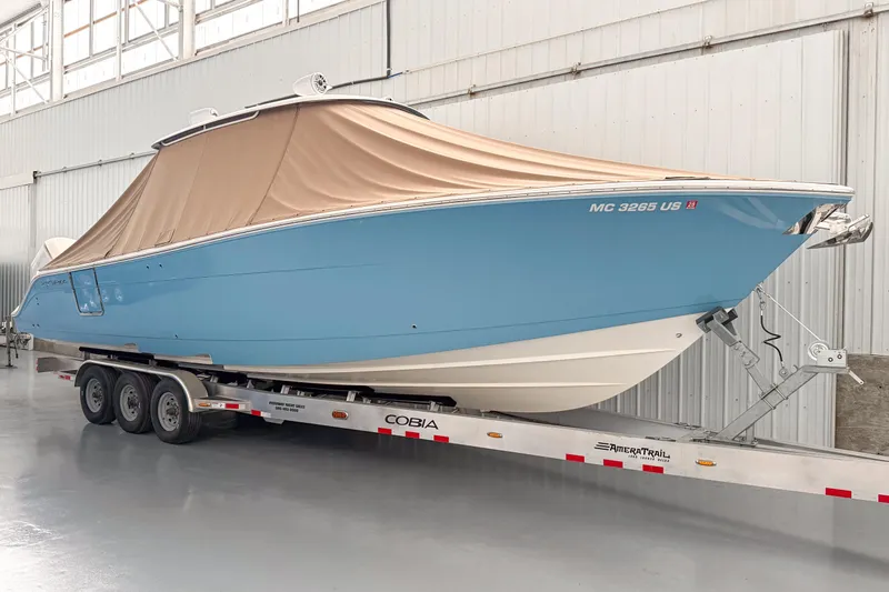 Slide: The Image of 2021 Cobia 350 CC boat with cover on trailer in indoor storage. - 0