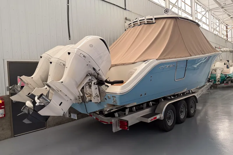 Slide: The Image of 2021 Cobia 350 CC boat with triple outboard engines on a trailer in a warehouse. - 1