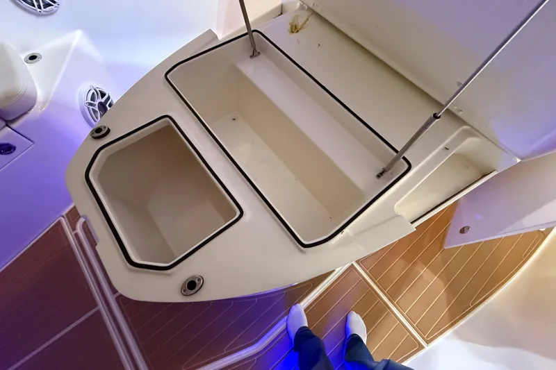 Slide: The Image of 2021 Cobia 350 CC boat storage compartments with open lids and wooden flooring. - 24