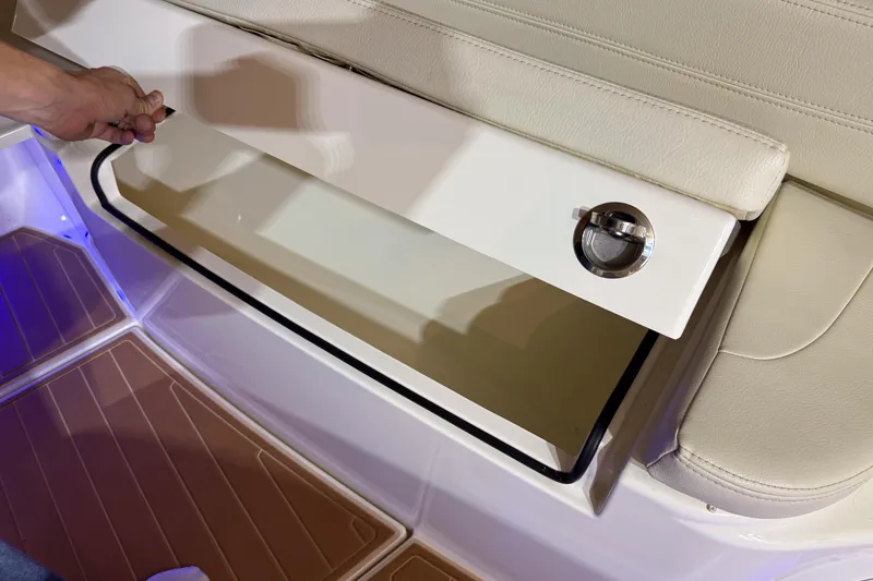 Slide: The Image of 2021 Cobia 350 CC boat storage compartment with beige seating and blue lighting. - 27