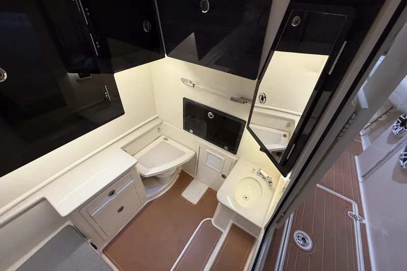 Slide: The Image of 2021 Cobia 350 CC boat interior bathroom with sink, toilet, and storage cabinets. - 29
