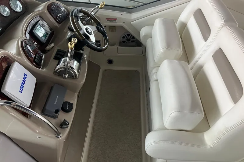 Slide: The Image of 2004 Sea Ray 320 Sundancer helm with white seating and navigation equipment. - 13
