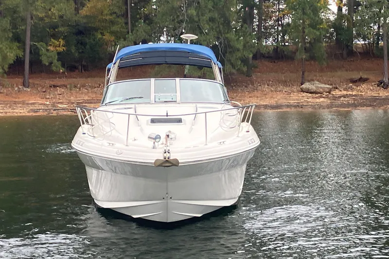 Slide: The Image of 2004 Sea Ray 320 Sundancer boat on calm water, surrounded by trees. - 2