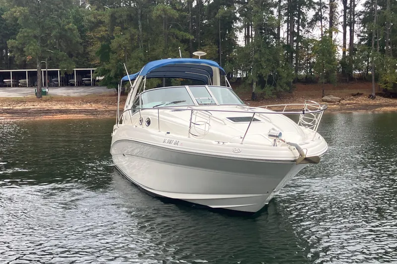 Slide: The Image of 2004 Sea Ray 320 Sundancer boat on a calm lake near a wooded shoreline. - 3