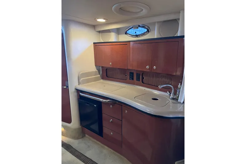 Slide: The Image of 2004 Sea Ray 320 Sundancer interior kitchen with wooden cabinets and modern sink. - 35