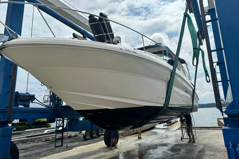 Slide: The Image of 2004 Sea Ray 320 Sundancer yacht being lifted at a marina under a cloudy sky. - 39