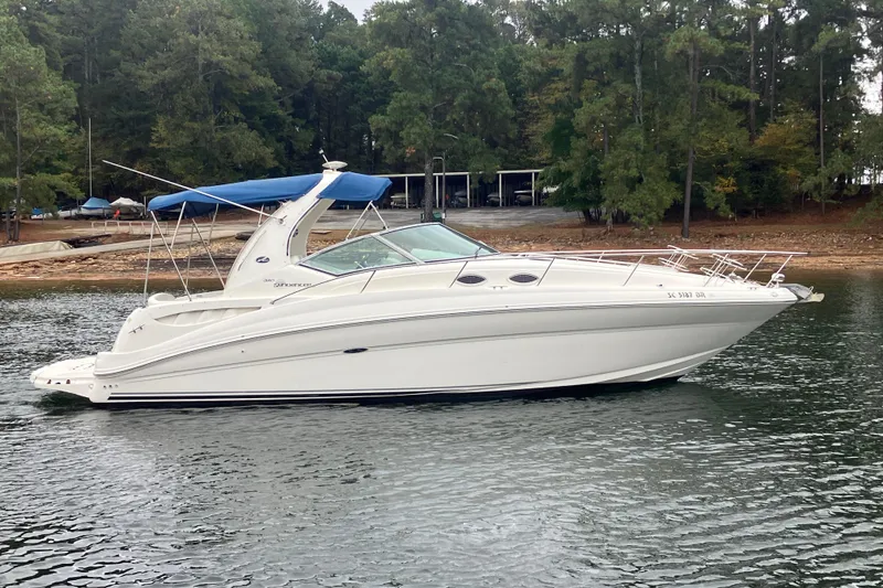 Slide: The Image of 2004 Sea Ray 320 Sundancer boat on a calm lake with forested shoreline. - 4