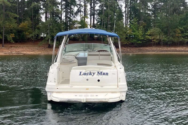 Slide: The Image of 2004 Sea Ray 320 Sundancer boat on water, forested shoreline in background. - 6