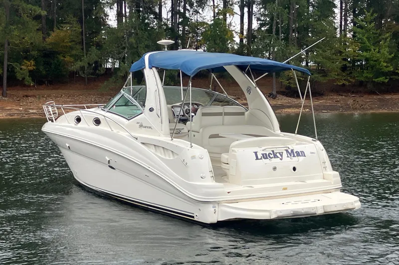 Slide: The Image of 2004 Sea Ray 320 Sundancer boat with blue canopy on a calm lake. - 7