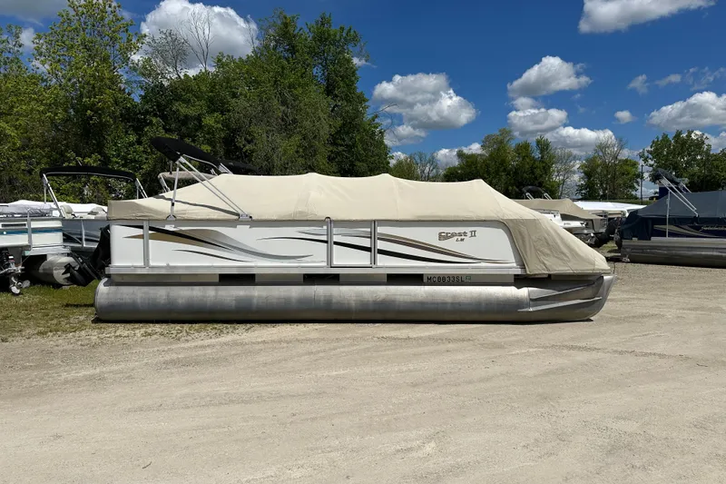 Slide: The Image of 2003 Crest 25 II LM pontoon boat covered, parked outdoors under a blue sky. - 2