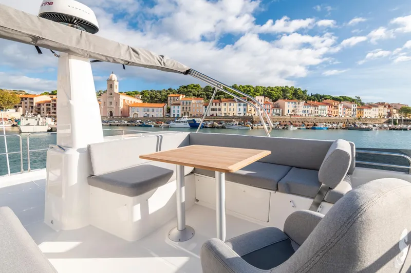 Slide: The Image of 2025 Beneteau Swift Trawler 41 Fly, spacious deck with seating, scenic waterfront view. - 11